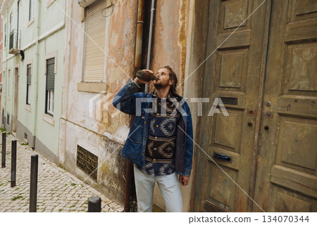 Candid shot of individual strolling city street with coffee Candid shot of individual strolling city street with coffee 134070344
