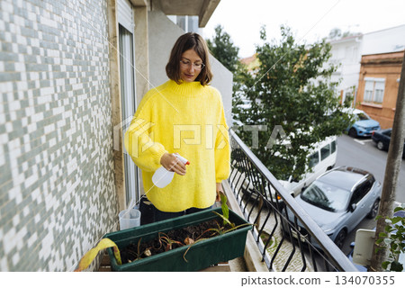 Creating cozy city balcony area with vibrant plants and natural light 134070355