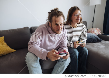Pair of grownups intensely competing in console games at home Pair of grownups intensely competing in console games at home 134070388