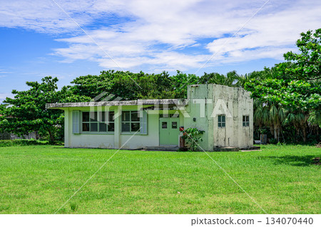 石垣島上，一座古老的混凝土建築被綠樹環繞，藍天白雲籠罩。 134070440