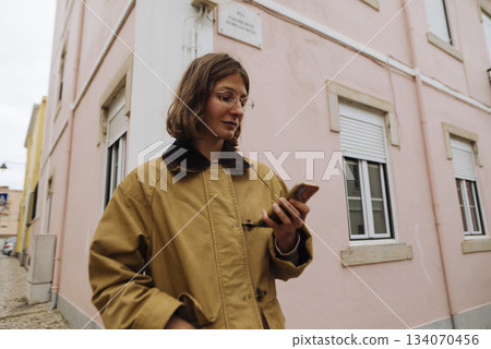 Calm woman in pastel architecture reading text on street corner 134070456
