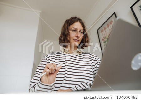 Professional Woman Editing Notes in Cozy Home Environment Professional Woman Editing Notes in Cozy Home Environment 134070462