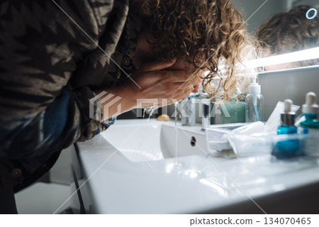 Bright mirror illuminates tired coder in modern apartment setting 134070465