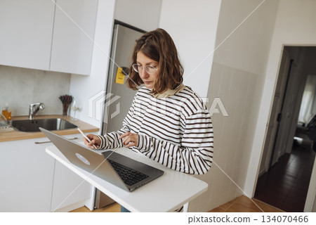 Professional woman conducting online conference from kitchen 134070466