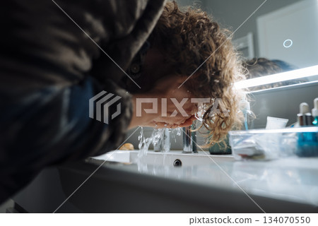 Passenger freshening up at small sink with mirror and essentials 134070550