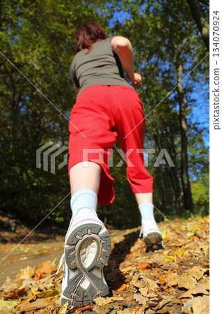 Woman walking cross country trail in autumn forest 134070924