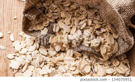 oat flakes cereal in burlap sack on wooden table. 134070951