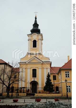 A yellow baroque church in Sremski Karlovci, Serbia, with an arched entrance and quiet courtyard. A concept of faith, heritage, and identity A yellow baroque church in Sremski Karlovci, Serbia, with an arched entrance and quiet courtyard. A concept of faith, heritage, and identity 134071496