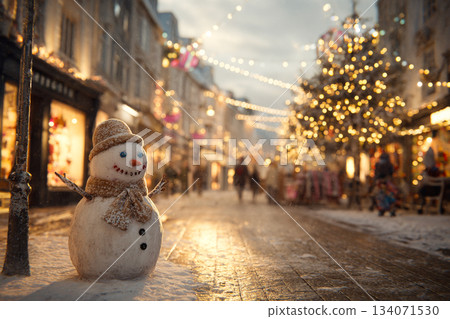 A cheerful snowman dressed warmly stands in the middle of a snowy pedestrian street. Surrounding shops glow with festive lights, creating a cozy winter atmosphere. 134071530