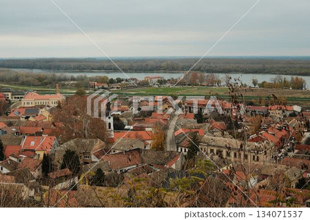 Sremski Karlovci rooftops with church tower and river landscape stretching into the distance. The scene expresses culture and old-town charm Sremski Karlovci rooftops with church tower and river landscape stretching into the distance. The scene expresses culture and old-town charm 134071537