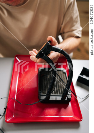 Close-up hands of technician person performing computer cooling system maintenance, disassembling liquid cooler components for cleaning and repair, focusing on hardware upgrade and technology service. 134072025