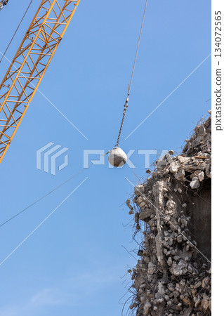 Heavy wrecking ball crane demolishing old building against blue sky in Magdeburg Germany. Building dismantling and construction waste disposal recycling service Heavy wrecking ball crane demolishing old building against blue sky in Magdeburg Germany. Building dismantling and construction waste disposal recycling service 134072565