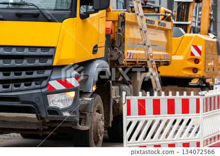 Sity street renovation rebuilding construction site with dump truck flasher excavator digging earth undeground infrastructure sewerage engineering system. Public municipal urban works sidewalk road 134072566
