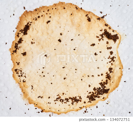 Round dried coffee stain on a textured white paper napkin, viewed from above Round dried coffee stain on a textured white paper napkin, viewed from above 134072751