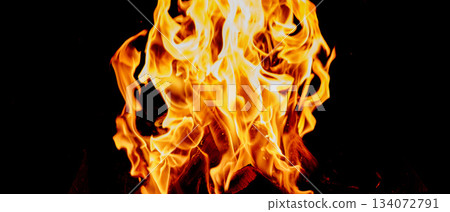 Close-up of tall bright flames, tongues of fire and orange-yellow glow above burning logs 134072791