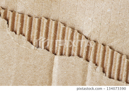 Close-up view of torn cardboard, rough texture and exposed corrugated layer, raw material detail. Natural background for scrapbooking, handmade collage Close-up view of torn cardboard, rough texture and exposed corrugated layer, raw material detail. Natural background for scrapbooking, handmade collage 134073390