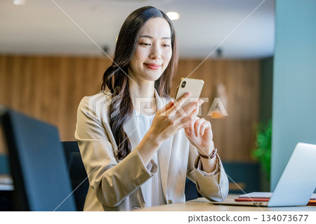 經營一部智能手機的女商人在辦公室 134073677