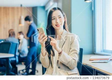 經營一部智能手機的女商人在辦公室 134073679
