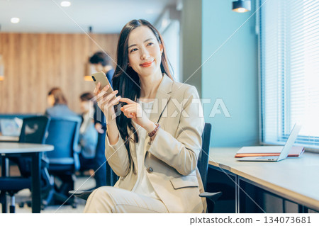 經營一部智能手機的女商人在辦公室 134073681