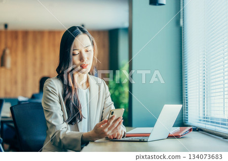 經營一部智能手機的女商人在辦公室 134073683