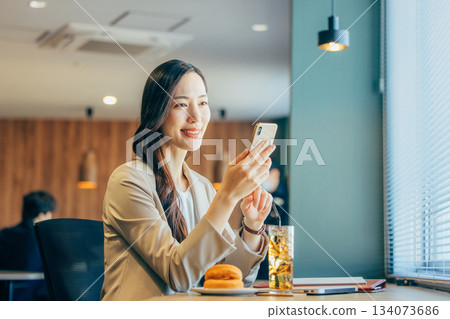 Businesswoman looking at smartphone in coworking space Businesswoman looking at smartphone in coworking space 134073686