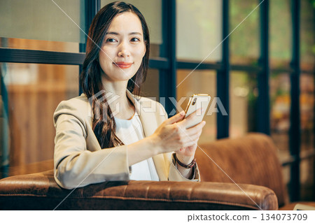 A woman using a smartphone in a cafe 134073709