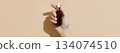 A womans hand holding a brown bottle of serum on a beige background. Body care  134074510