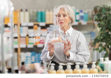 Elderly woman in summer clothes looking for medicine in pharmacy 134074859