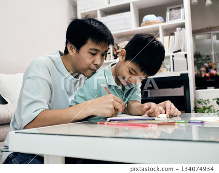 Father helping child with drawing at home; learning, creativity, and quality family time in warm and supportive environment ideal for education and parenting concepts 134074934