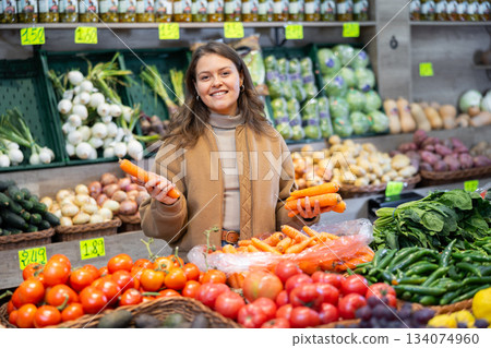 Young woman choosing carrots in vegetable shop Young woman choosing carrots in vegetable shop 134074960