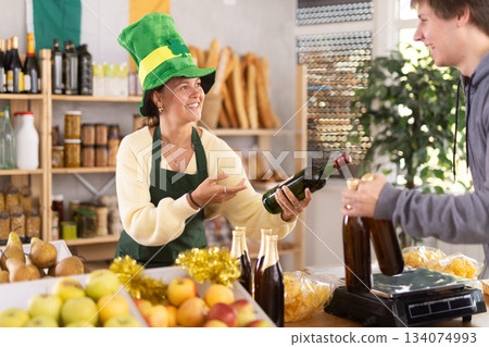 Female vendor in Irish green cap offers Irish ale to male customer Female vendor in Irish green cap offers Irish ale to male customer 134074993