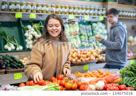 Young woman choosing tomatoes in vegetable shop 134075016