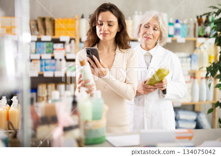 Adult European woman scans shampoo barcode in front of pharmacist 134075042