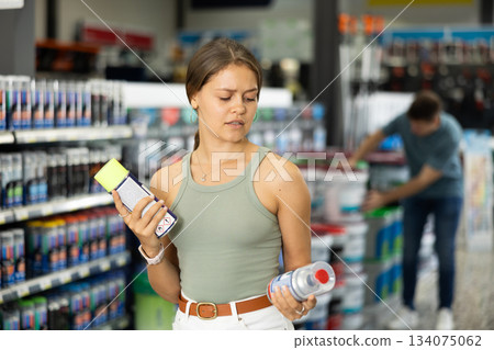 Young woman choose cans of aerosol paint in hardware store Young woman choose cans of aerosol paint in hardware store 134075062