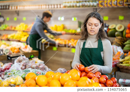Young woman seller lays out tomatoes on counter Young woman seller lays out tomatoes on counter 134075065