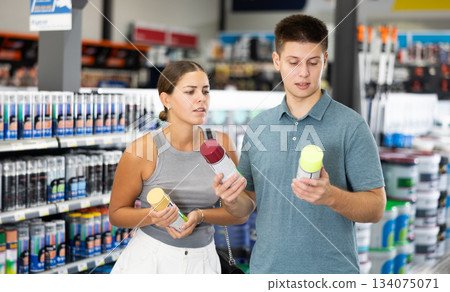 Positive couple choosing acrylic paint spray in building supermarket Positive couple choosing acrylic paint spray in building supermarket 134075071