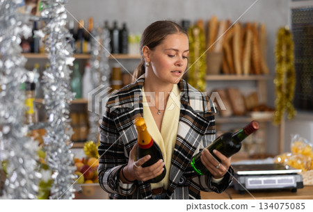 On New Years Eve, girl shopper compare wine and champagne, buys alcoholic beverages 134075085