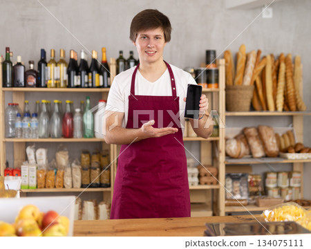 Man in an apron holds a phone in a store 134075111