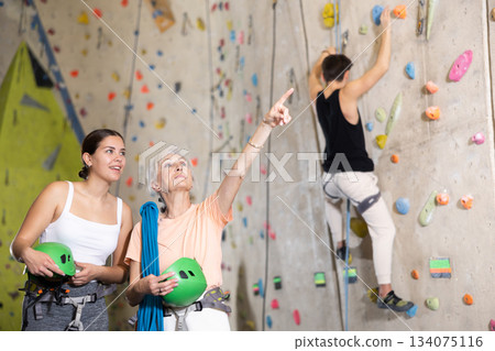 two active female marathon participants are standing in climbing hall 134075116