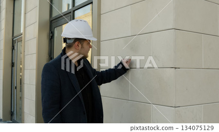 Male architect or builder inspecting the quality of a wall structure on the site 134075129