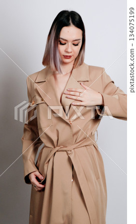 Woman in a nude silk pajama set posing with a seductive look and bare shoulder Woman in a nude silk pajama set posing with a seductive look and bare shoulder 134075199