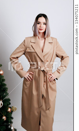 Woman in a nude silk pajama set posing elegantly with a hand near her neck 134075211