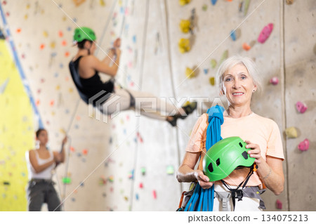Senior confident female climber with her equipment getting ready for training 134075213