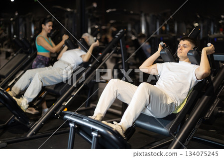 Guy using hack squat machine in modern gym 134075245