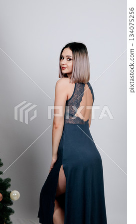 Woman in a dark blue chemise or nightgown posing elegantly in a studio Woman in a dark blue chemise or nightgown posing elegantly in a studio 134075256