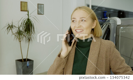 Woman client talking on a phone,possibly discussing the car purchase decision Woman client talking on a phone,possibly discussing the car purchase decision 134075342
