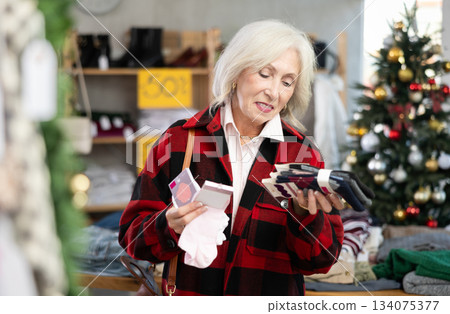 Mature woman choosing socks in a Christmas store Mature woman choosing socks in a Christmas store 134075377