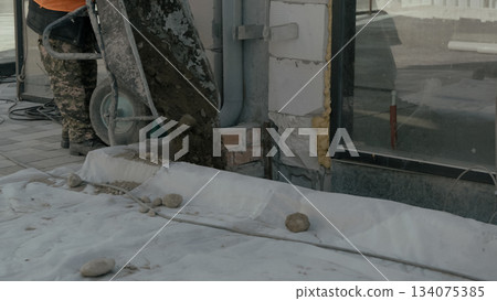 A construction machine is cutting the base of the wall 134075385