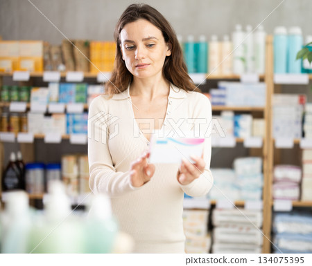 Girl in summer clothes looking for medicine in pharmacy 134075395