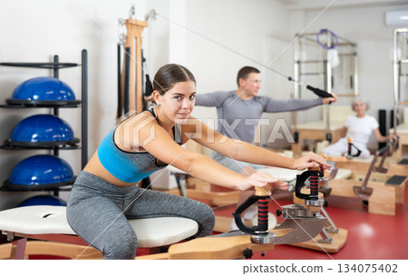 Young woman stretching her arms using pilates machine 134075402